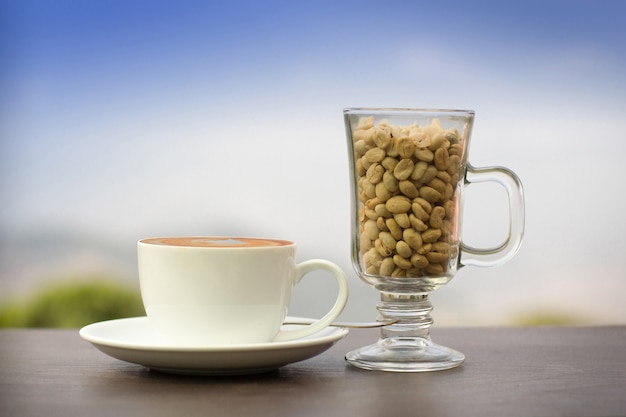 Xícara de café e sementes de feijão na mesa no fundo da natureza