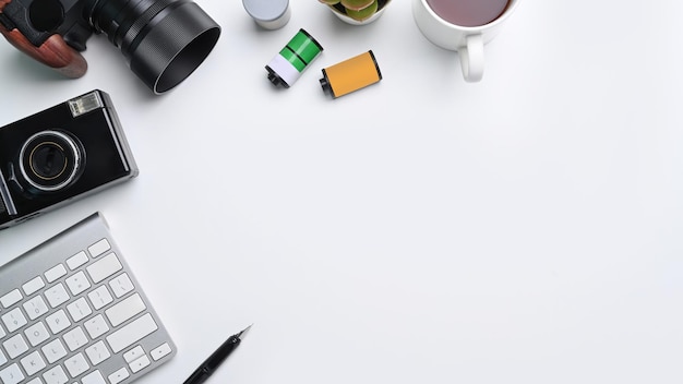 Xícara de café e teclado de acessórios de câmera no espaço de trabalho do fotógrafo