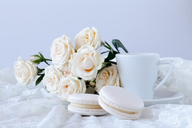 Xícara de café e um buquê de rosas brancas