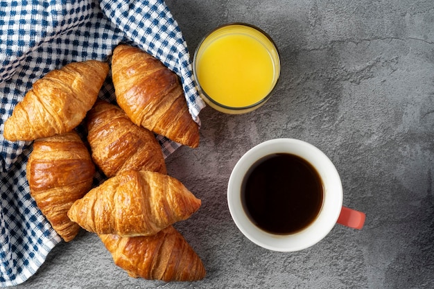 Xícara de café e um copo de suco de laranja junto com pequenos croissants ricos prontos para o café da manhã