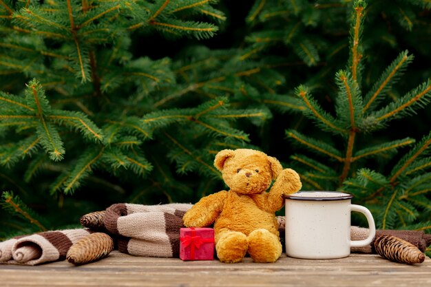 Xícara de café e urso de pelúcia com presente na mesa de madeira