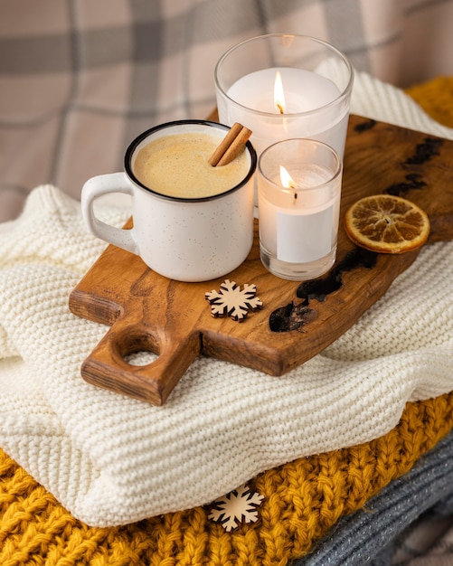 Xícara de café em ângulo alto com velas e paus de canela