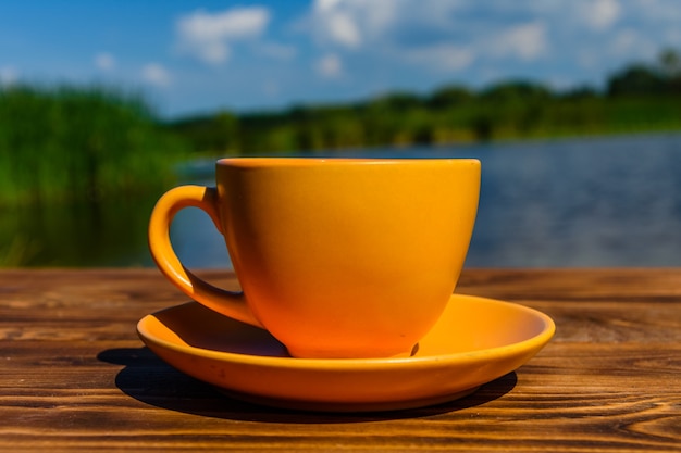 Xícara de café em mesa de madeira rústica à beira-rio