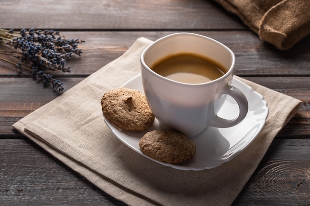 Xícara de café em um guardanapo de linho, grãos de café e visão horizontal do saco