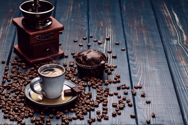 Xícara de café em uma mesa de madeira azul com grãos de café e chocolate