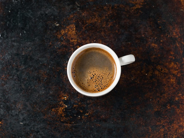 Xícara de café expresso branco e grãos torrados na velha mesa marrom enferrujada