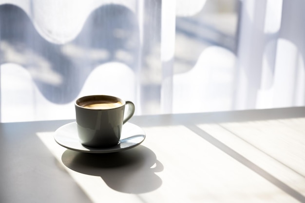 Xícara de café expresso na mesa perto da janela