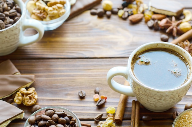 Xícara de café expresso preto sobre fundo de madeira natural com lanches saudáveis - nozes e passas. Copie o espaço no meio.