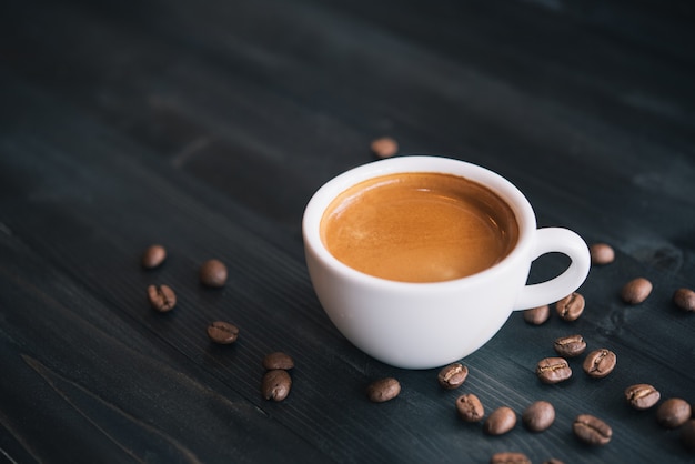 Foto xícara de café expresso saboroso fresco de café quente com grãos de café sobre fundo escuro