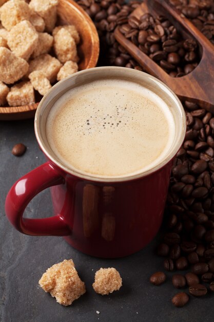 Xícara de café, feijão e açúcar mascavo na mesa de pedra