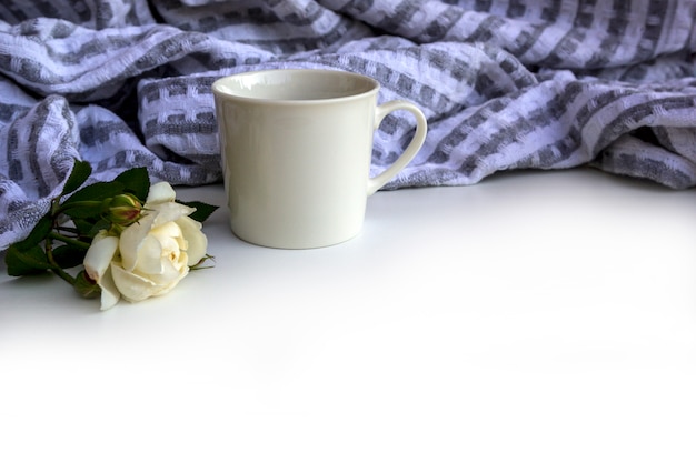 Xícara de café, flores e xadrez na mesa branca.