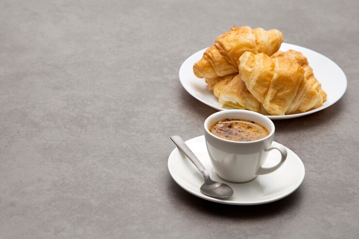 Xícara de café fresco com croissants em fundo escuro