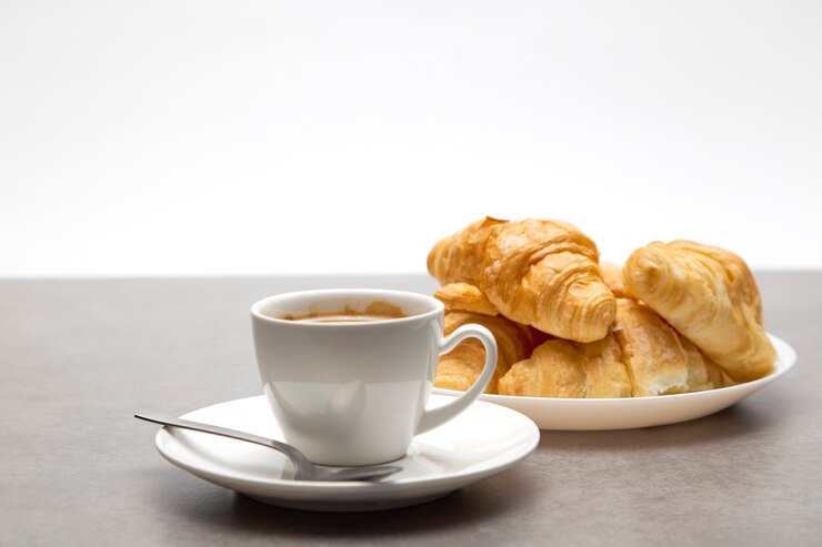 Xícara de café fresco com croissants em fundo escuro