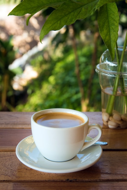 Xícara de café fresco com grãos de café na mesa de madeira