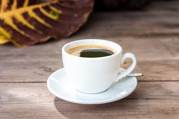 Xícara de café fresco com grãos de café na mesa de madeira