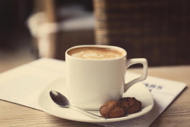 Xícara de café fresco e jornal da manhã na mesa de madeira