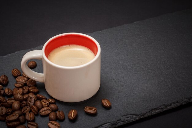 Xícara de café, grãos de café em fundo preto. Vista do topo.