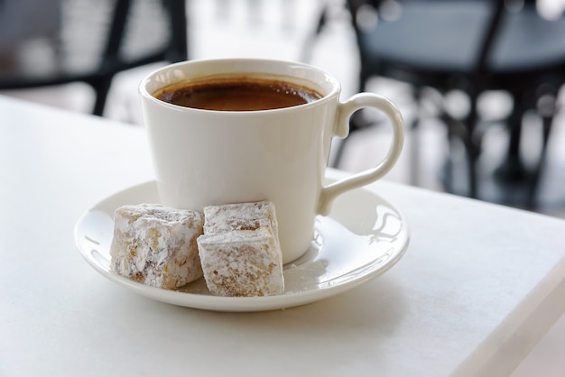 Xícara de café grego - turco, isolado na mesa branca com doce deleite