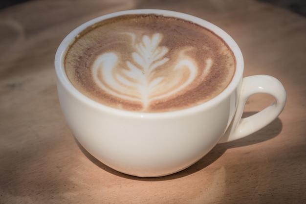 xícara de café latte na mesa de madeira, tom suave