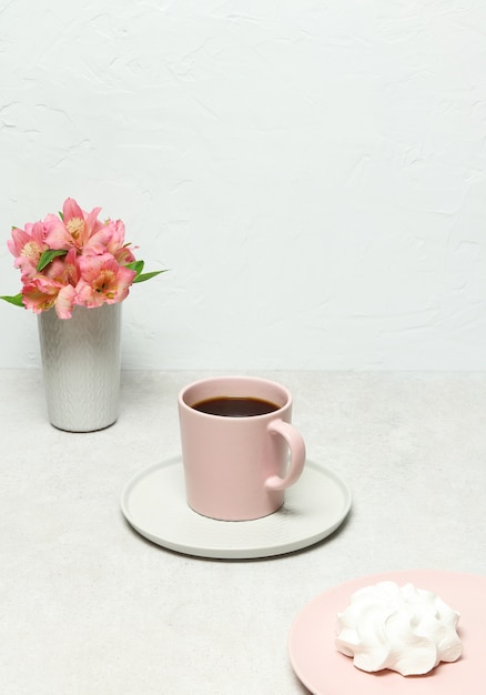 Xícara de café, marshmallow branco, flores na mesa de pedra cinza