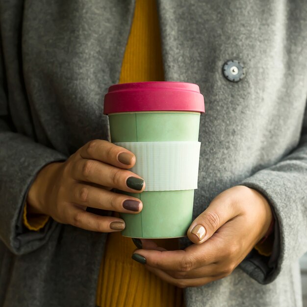 Xícara de café moderna no conceito de zero desperdício nas mãos de uma mulher