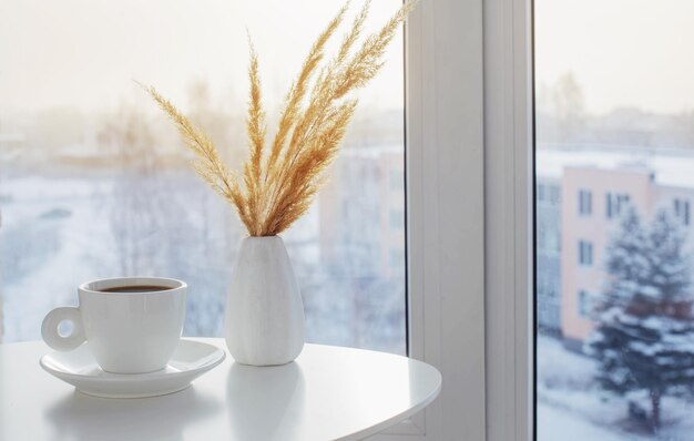 Xícara de café na mesa branca perto da janela no inverno