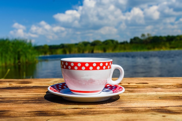 Xícara de café na mesa de madeira à beira do rio