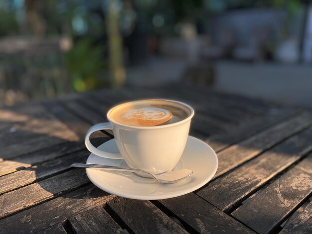 Xícara de café na mesa de madeira no café com luz de fundo da manhã