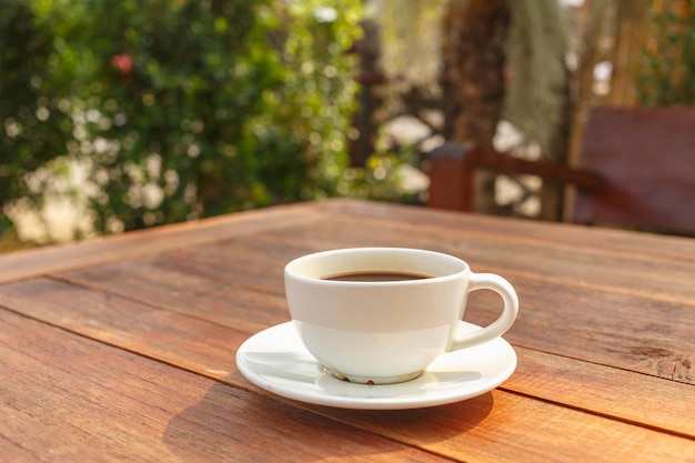 Xícara de café na mesa de madeira no sol da manhã