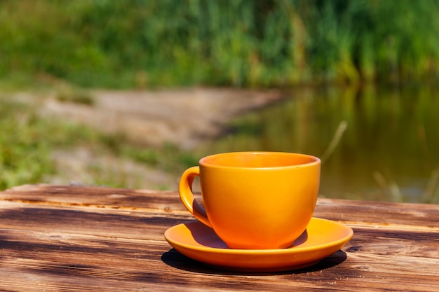 Xícara de café na mesa de madeira perto do rio