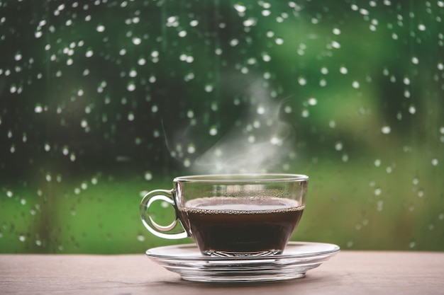 Xícara de café na mesa dentro da janela, coffee break pela manhã com dia chuvoso