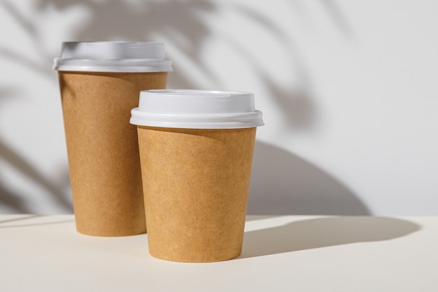 Xícara de café para viagem com sombras de folhagem, copie o espaço
