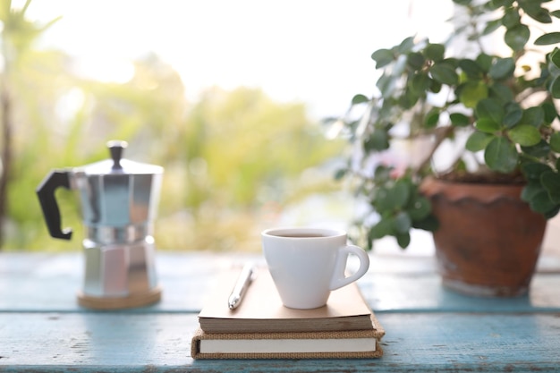 Xícara de café pequena e notebook e vaso de plantas