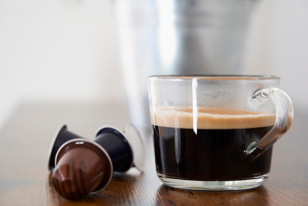 Xícara de café preto ao lado de algumas cápsulas Nespresso