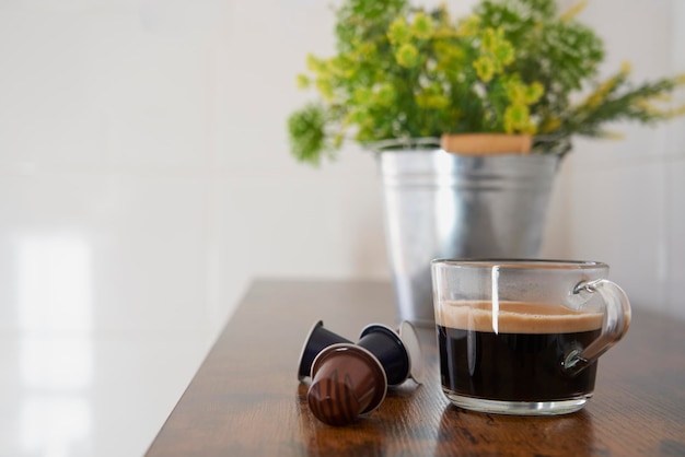 Xícara de café preto ao lado de algumas cápsulas Nespresso