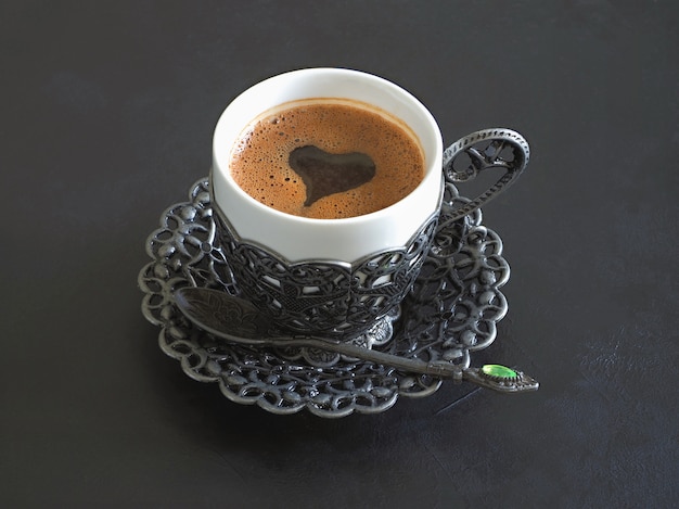 Xícara de café preto com forma de coração na mesa preta