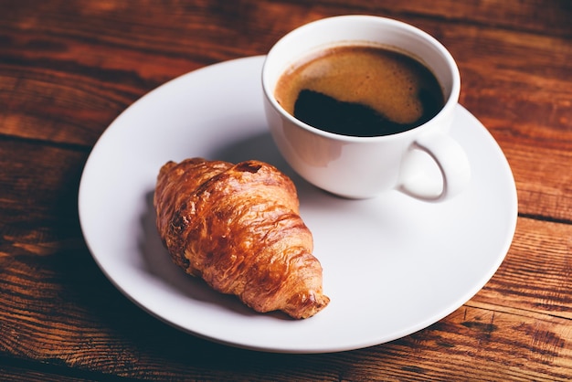 Xícara de café preto e croissant fresco