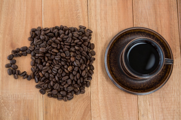 Xícara de café preto e grãos de café em forma de xícara