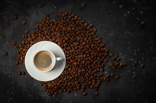 Xícara de café preto e grãos de café torrados na vista superior de fundo cinza escuro, espaço livre para texto.