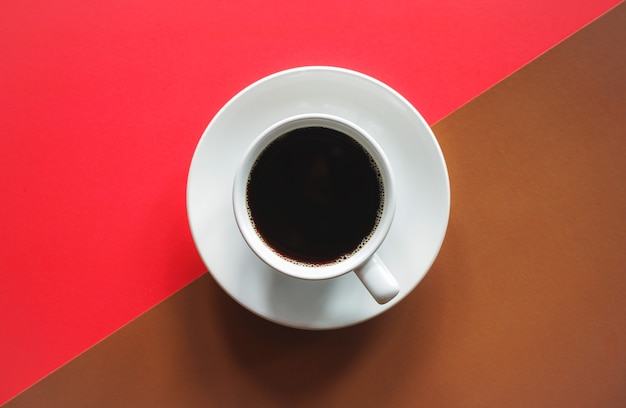 Xícara de café preto em fundo vermelho e marrom abstrato