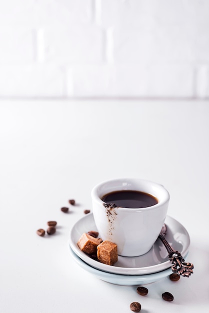 Xícara de café preto em um pires com açúcar mascavo em um fundo branco