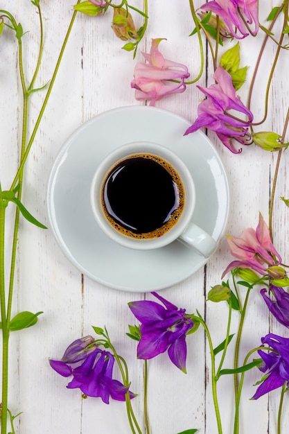 Xícara de café preto em um pires entre as flores