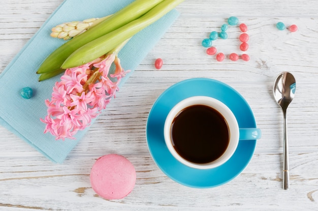 Xícara de café preto, flores cor de rosa e macaroons franceses