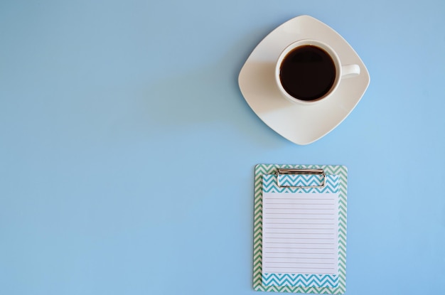 Xícara de café preto quente com caneta de papel para caderno Vista superior Copiar espaço Plano horizontal sobre fundo azul