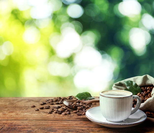 Xícara de café quente aromático e feijão na mesa de madeira ao ar livre Espaço para texto