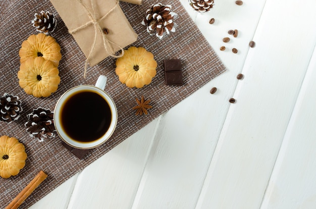 Xícara de café quente com bolos, pacotes de ano novo e pinhas