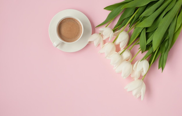 Xícara de café quente com buquê de tulipas