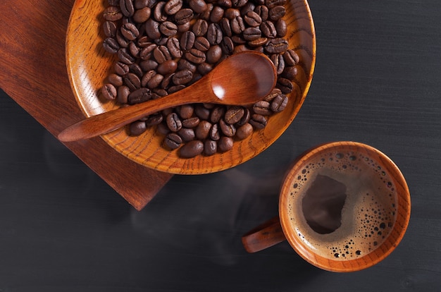 Xícara de café quente com feijão em pires de madeira