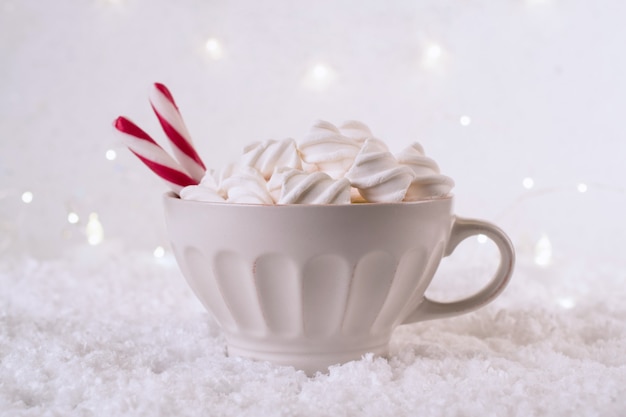 Xícara de café quente com marshmallows e pirulito vermelho em um inverno gelado