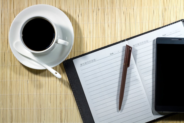 Foto xícara de café quente com notebook e celular sobre o empresário de mesa